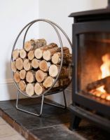 The 69.5cm Pewter Finish Circular Log Rack & Holder Shown at an angle next to a Traditional Log Burner Stove - Digital Illustration The 69.5cm Pewter Finish Circular Log Rack & Holder Shown at an angle next to a Traditional Log Burner Stove - Digital Illustration