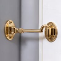 The 6 Inch Brass Cabin Hook Silent Type on a Grey Internal Wall Holding Open a White Door - Digital Illustration 