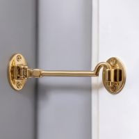 The 8 Inch Brass Cabin Hook Silent Type Heavy on a Grey Wall Holding Open a White Door - Digital Illustration 