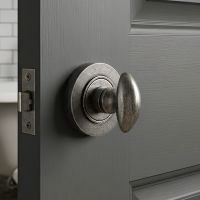 The Aged Pewter Concealed Thumbturn Set with Plain Cover on a Grey Door Leading to a Bathroom - Digital Illustration