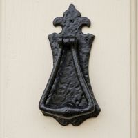 The Antique Black Iron Gothic Style Fleur De Lys Door Knocker on a Cream Coloured Front Door to a Country Cottage - Digital Illustration