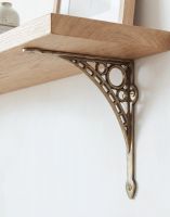 The Antique Brass 20cm x 22cm "Iron Bridge" Shelf Bracket Mounted on a White Coloured Living Room Wall - Digital Illustration.