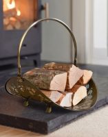 The Antique Brass Curved Log Rack & Holder With Handle on a Stone Hearth in Front of a Log Burner Stove - Digital Illustration The Antique Brass Curved Log Rack & Holder With Handle on a Stone Hearth in Front of a Log Burner Stove - Digital Illustration