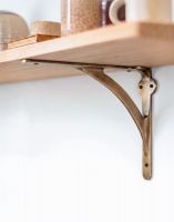 The Antique Brass Stylish Architectural Shelf Bracket USed as a Decorative Wall Hanger on a Wooden Shelf - Digital Illustration