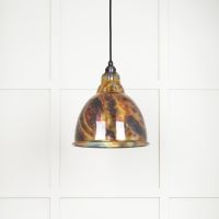 The Aura Dome Pendant Light in Burnished Brass Shown Lit up on a White Panelled Background