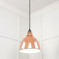 The Aura Dome Pendant Light in Copper and White Gloss Shown at a Low Angle Whilst Lit up 