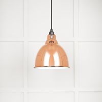 The Aura Dome Pendant Light in Copper and White Gloss Shown Lit up on a White Panelled Background