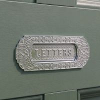 The Aztec Style Letter Plate in a Polished Chrome Finish on a Complementary Green Coloured Wooden Door - Digital Illustration The Aztec Style Letter Plate in a Polished Chrome Finish on a Complementary Green Coloured Wooden Door - Digital Illustration