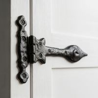 The Black Cast Iron Antique Door Hinge Pair Shown Close up on a Well Lit Wooden Door - Digital Illustration