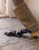 The Black Dog and Bone Boot Jack Placed at the Entrance of a Rustic Cottage Porch Viewed from the Side- Digital Illustration