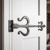 The Black Traditional Fleur-De-Lys Iron Door Hinges Shown Fitted on a Bright White Door in a Cosy Modern Home - Digital Illustration 
