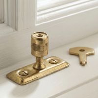 The Casement Stay Locking Pin in Front of a Wooden Window Frame in a Country Home in a Gold Plated Finish - Digital Illustration The Casement Stay Locking Pin in Front of a Wooden Window Frame in a Country Home in a Gold Plated Finish - Digital Illustration