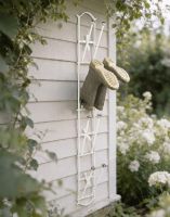 The Cream Brackenfell 4 Pair Wall Mounted Boot Rack Fixed to a Wooden Exterior Garden Wall - Digital Illustration 