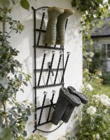 The Edcote Black Wall Mounted 6 Pair Boot Rack Mounted on a White Coloured Exterior Wall