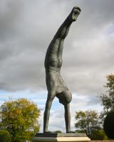 The Equilibrium Handstand Garden Sculpture in Verdigris Displayed in an Ornate Garden