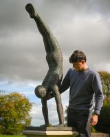 The Equilibrium Handstand Garden Sculpture in Verdigris Shown with a Man Stood Next to the Sculpture