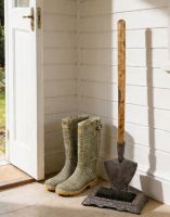 The Esther Garden Spade Boot Scraper & Brush Positioned Next to a Garden Entranceway - Digital Illustration 