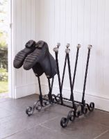 The Farnthorpe Black 4 Pair Ornate Boot Rack On a Stone Tiled Floor in a Sunny Porch - Digital Illustration 