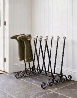 The Haldenwall 6 Pair Boot Rack in Black Placed in a Stone Tiled Cottage Porch Close up View - Digital Illustration The Haldenwall 6 Pair Boot Rack in Black Placed in a Stone Tiled Cottage Porch Close up View - Digital Illustration