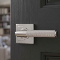 The Knurled Sprung Handle Set on a Square Rose in Satin Stainless Steel shown close up on a Grey Door - Digital Illustration 