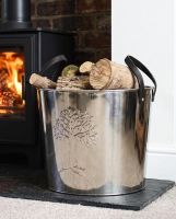 The Large Polished Steel "Tree of Life" Log Bucket next to a Lit Log Burner in a Modern Home Setting - Digital Illustration