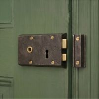 The Left Handed "Lazio" Small Iron Rim Lock Mounted on a Green Door in a Traditional Home - Digital Illustration