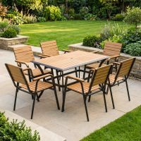 The Linea 6-Seater Outdoor Garden Dining Set in Teak in a Sunny Low Walled Garden Surrounded by Plants