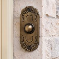 The "Mackintosh" Antique Brass Ornate Bell Push on a Cream Coloured Stone Wall next to a Front door - Digital Illustration 