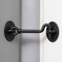 The Matte Black Cabin Hook and Eye Latch Shown Fitted in a Modern Home on a Grey Wall next to a White Door - Digital Illustration 