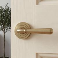 The Modern Satin Brass "Neville" Art Deco Door Handle on Rose Set on a Classic Cream Coloured Wooden Interior Door - Digital Illustration