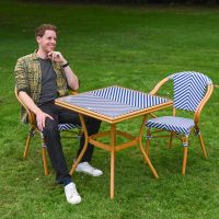 The Nizza Chevron Square Bistro Set in Blue & White With a Man Sat down on a Chair on a Garden lawn