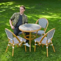 The Orbis Diamond 4-Seater Bistro Dining Set in Black & White With a Man Sat down on a Chair on a Garden lawn
