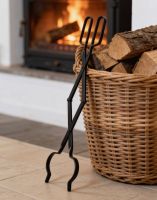 The “Prism” Steel Fire Place Tongs Leaned up against a Log basket with a Modern Log Burner in the Background - Digital Illustration