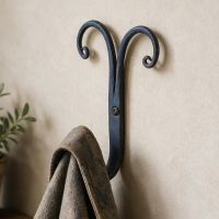 The "Rams Horn" Scrolled Iron Coat hook Shown on a Wall with a Coat Hung up on it - Digital Illustration
