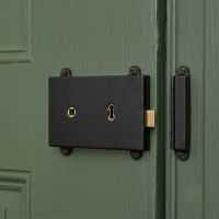 The Reversible "Bamburgh" Iron Rim Lock Mounted on a Green Wooden Door Entrance - Digital Illustration