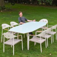 The Riviera 8-Seater Outdoor Dining Set on a Garden Lawn with a Man Sat at the Table Relaxing