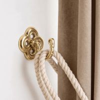 The “Riviera” Curtain tie back Fixed on a White Interior Wall Next to a Curtain - Digital Illustration