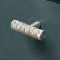 The Aged Brass "Astor" Knurled Industrial T-Bar Cabinet Handle Mounted on a Dark Blue Kitchen Cupboard Drawer - Digital Illustration The Aged Brass "Astor" Knurled Industrial T-Bar Cabinet Handle Mounted on a Dark Blue Kitchen Cupboard Drawer - Digital Illustration