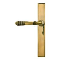 The Slimline Lever Espagnolette Door Latch in Aged Brass shown on a White Background with Handle Facing to the Left