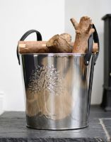The Small Polished Steel "Tree of Life" Log Bucket on a Stone Hearth next to a Log Burner Stove - Digital Illustration The Small Polished Steel "Tree of Life" Log Bucket on a Stone Hearth next to a Log Burner Stove - Digital Illustration