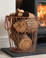 The Small Rose Gold Wire Log Basket Filled with Logs next to a Traditional Log Burner Stove - Digital Illustration