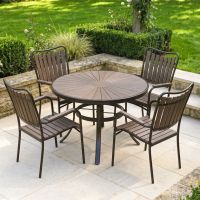 The Solis Round 4-Seater Outdoor Dining Set in Coffee Shown on a Sunny Patio in a Walled Garden