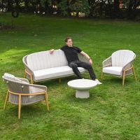 The Soria Woven 4-Piece Outdoor Lounge Set Showing the Full Set with a Smiling Man Relaxing on the Bench