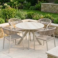 The Soria Woven 4-Seater Dining Set Displayed in a Sunny Low walled Garden Surrounded by Plants