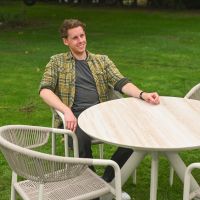 The Soria Woven 4-Seater Dining Set with a Smiling Man Sat at the Table Relaxing