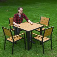 The Strata Slatted 4-Seater Outdoor Dining Set in Black With a Smiling Man Sat on one of the Chairs