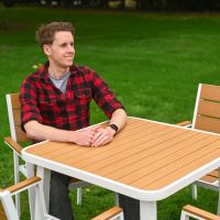 The Strata Slatted 4-Seater Outdoor Dining Set With a Smiling Man Relaxing at the Table