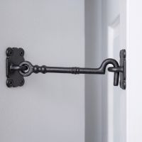 The Traditional Black Iron Large 16" Loose Ring Cabin Hook Fitted on a White Door next to a Grey Coloured Interior Wall - Digital Illustration
