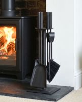 The Traditional Black Slim Three Piece Companion Set next to a Traditional Log Burner Stove in a Modern Home - Digital Illustration