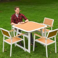 The Verve Quadrat 4 in Seater Outdoor Dining Set in White With a Man Sat at the Table Smiling